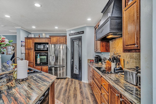 kitchen with backsplash, black appliances, light wood-type flooring, brown cabinets, and a textured ceiling