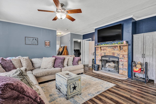 living room featuring ceiling fan, a stone fireplace, wood finished floors, and ornamental molding