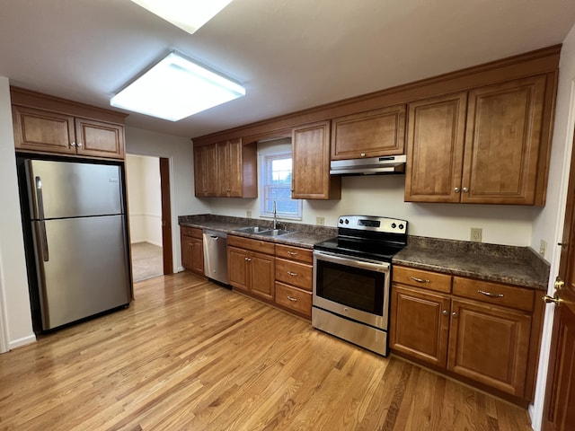 kitchen with appliances with stainless steel finishes, sink, and light wood-type flooring