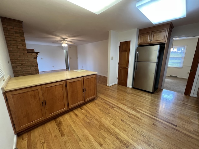 kitchen with ceiling fan, stainless steel fridge, and light wood-type flooring