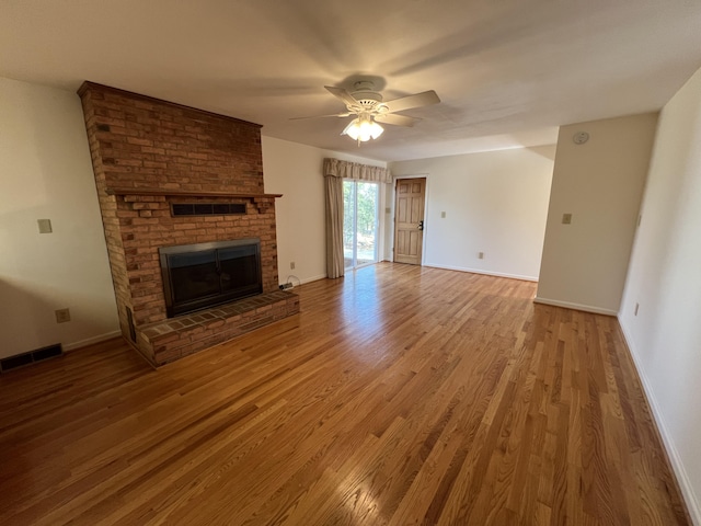 unfurnished living room with a brick fireplace, wood-type flooring, and ceiling fan