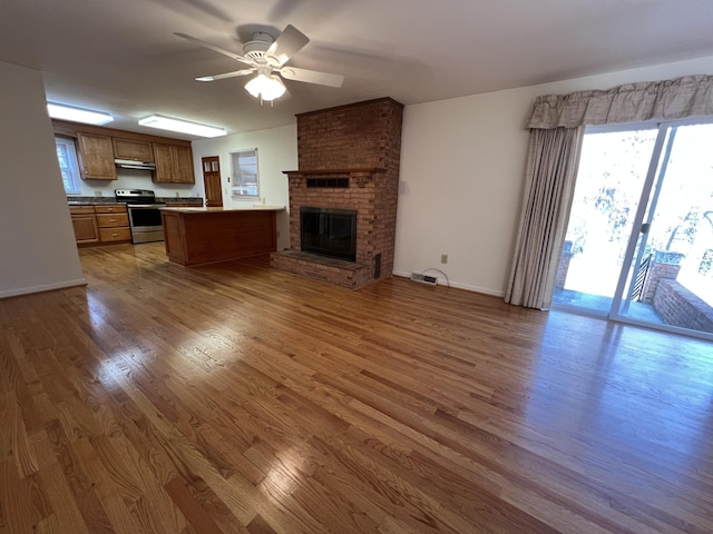 unfurnished living room with ceiling fan, dark hardwood / wood-style floors, and a brick fireplace