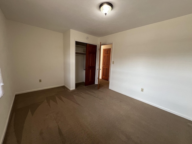 unfurnished bedroom featuring dark carpet and a closet