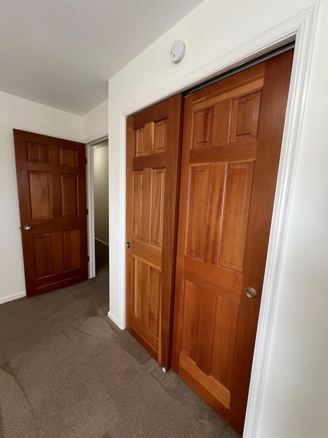 hallway featuring dark colored carpet