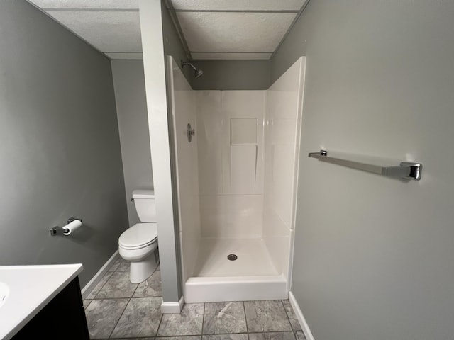 bathroom with toilet, a shower, a paneled ceiling, vanity, and tile patterned flooring