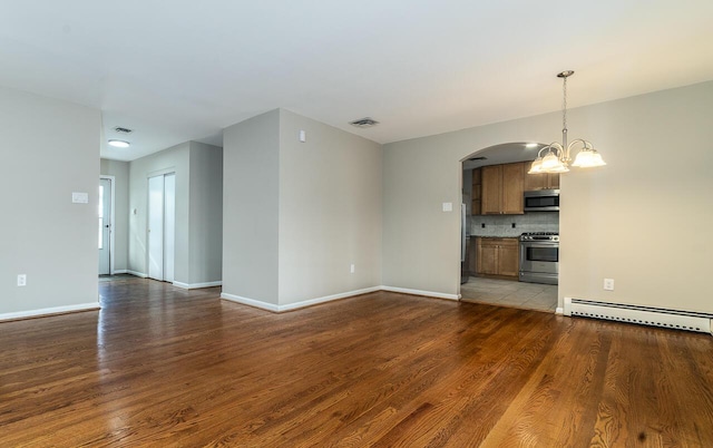 unfurnished living room featuring hardwood / wood-style flooring, a baseboard radiator, and an inviting chandelier