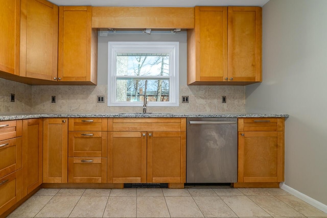 kitchen with light tile patterned flooring, tasteful backsplash, dishwasher, sink, and light stone counters