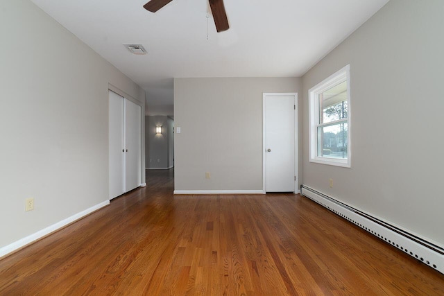 empty room with a baseboard heating unit, wood-type flooring, and ceiling fan