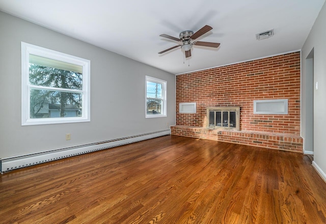 unfurnished living room featuring hardwood / wood-style flooring, ceiling fan, a baseboard heating unit, a fireplace, and brick wall