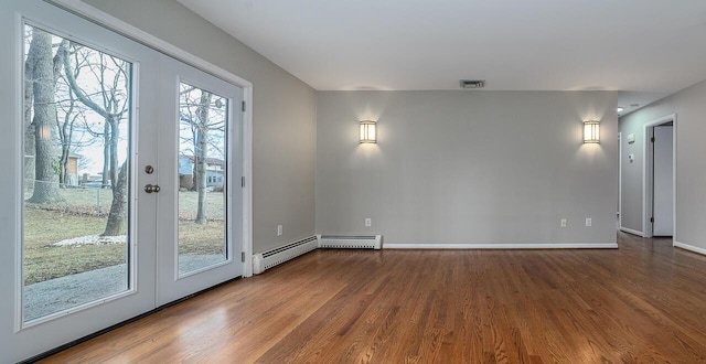 empty room featuring baseboard heating and hardwood / wood-style flooring