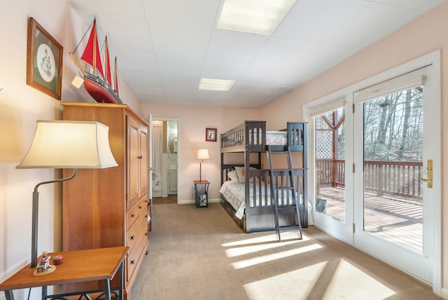 carpeted bedroom with a paneled ceiling and access to outside