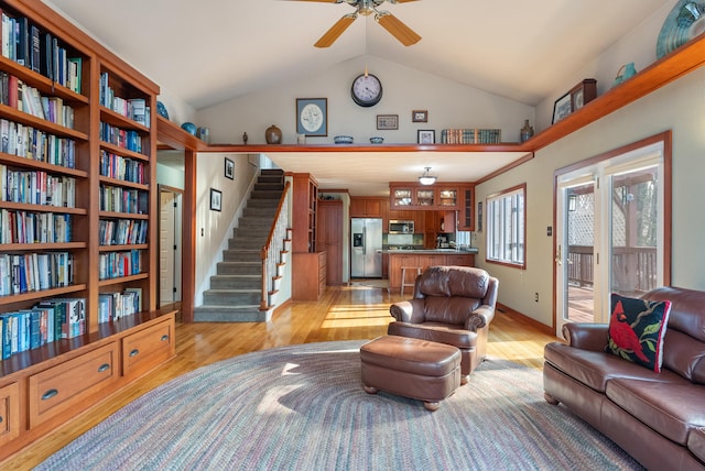 living room with ceiling fan, vaulted ceiling, and light hardwood / wood-style flooring