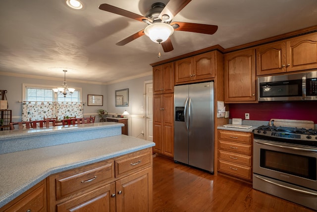 kitchen with brown cabinetry, appliances with stainless steel finishes, crown molding, and dark wood-type flooring