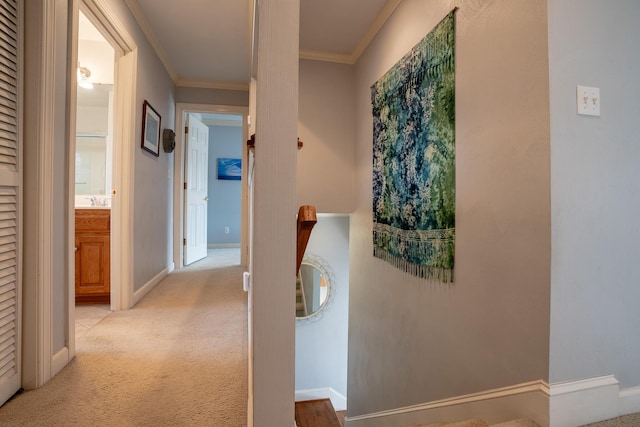 hallway with a sink, baseboards, light carpet, and crown molding