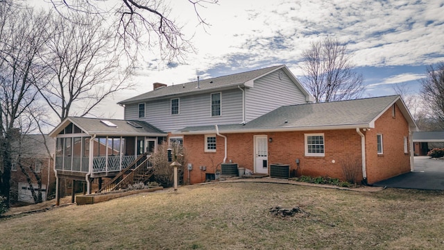 back of house with brick siding, a lawn, cooling unit, a chimney, and a sunroom