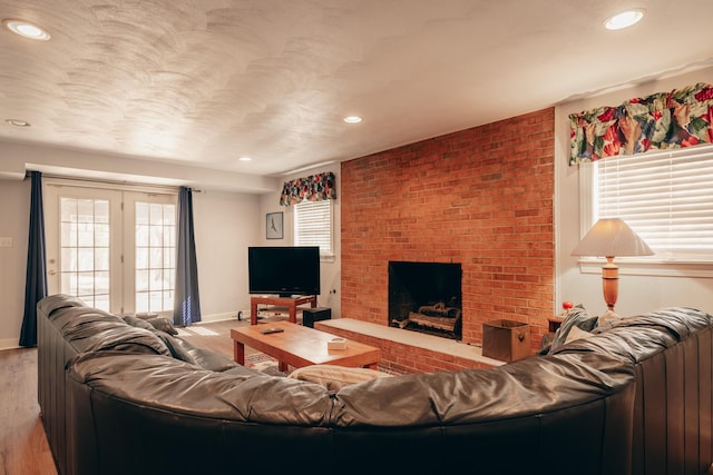 living area featuring recessed lighting, light wood-type flooring, baseboards, and a brick fireplace