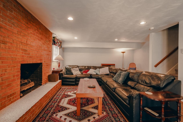 living room featuring a brick fireplace, stairway, recessed lighting, and brick wall