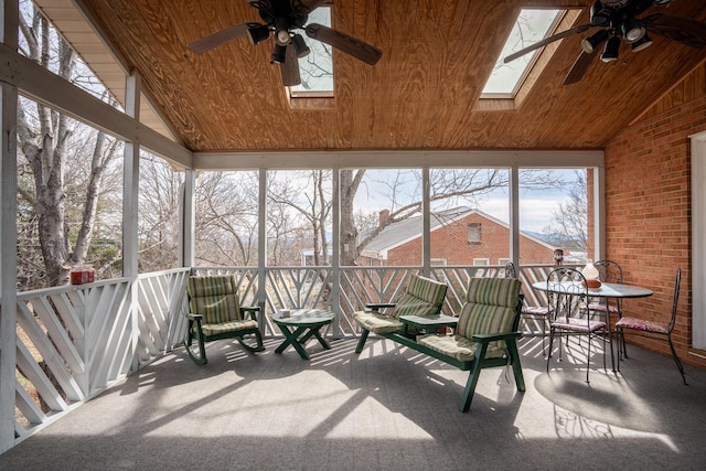 sunroom featuring lofted ceiling with skylight, ceiling fan, and wooden ceiling