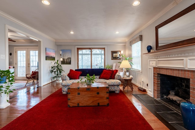 living room with baseboards, wood finished floors, a brick fireplace, and ornamental molding