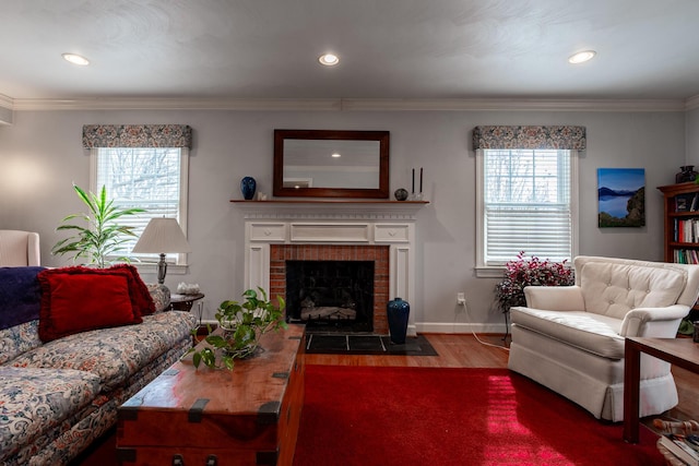 living area with a fireplace, wood finished floors, crown molding, and a healthy amount of sunlight