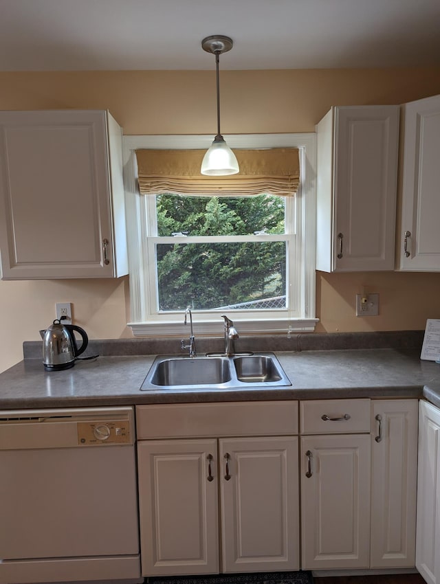 kitchen featuring white dishwasher, sink, decorative light fixtures, and white cabinets