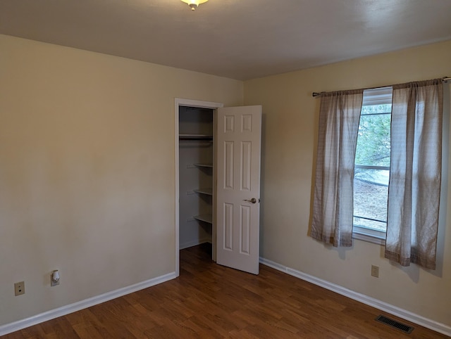 unfurnished bedroom with wood-type flooring, a spacious closet, and a closet