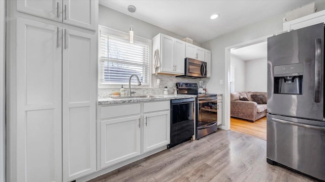 kitchen with sink, light hardwood / wood-style flooring, white cabinets, stainless steel appliances, and backsplash