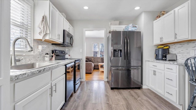 kitchen with white cabinetry, appliances with stainless steel finishes, sink, and light wood-type flooring