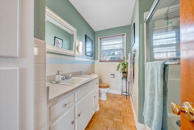 bathroom with tile walls, vanity, parquet flooring, and toilet