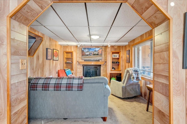 carpeted living room featuring a paneled ceiling and wooden walls