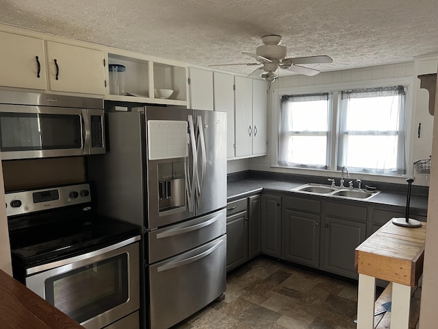 kitchen featuring sink, ceiling fan, appliances with stainless steel finishes, gray cabinetry, and a textured ceiling