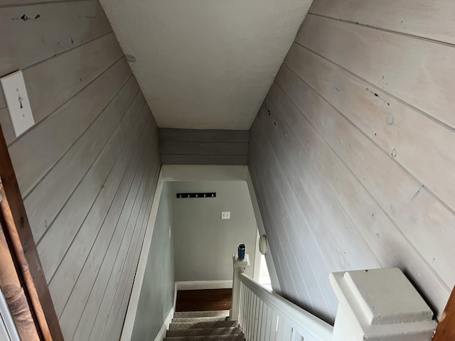 stairway featuring wooden walls