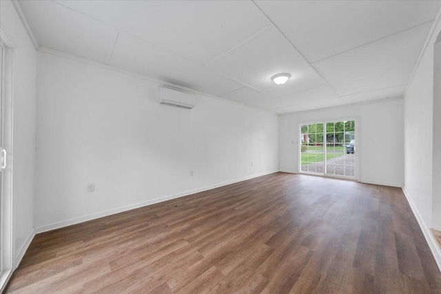 unfurnished room with a wall mounted air conditioner, baseboards, ornamental molding, and wood finished floors
