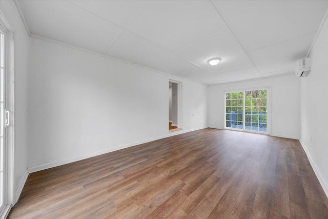 empty room with wood finished floors, baseboards, and a wall unit AC