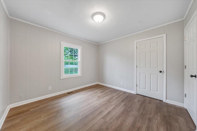 unfurnished bedroom featuring baseboards, crown molding, wood finished floors, and visible vents