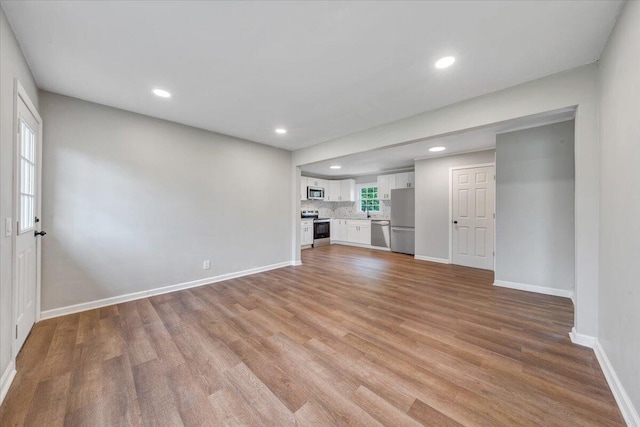 unfurnished living room featuring recessed lighting, light wood-type flooring, and baseboards