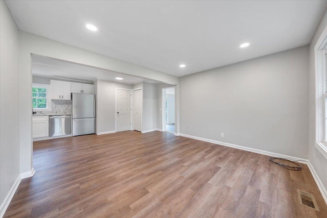 unfurnished living room featuring visible vents, light wood finished floors, and baseboards
