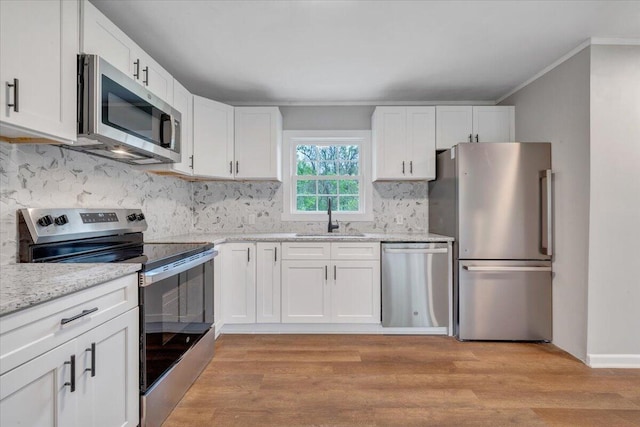 kitchen with a sink, white cabinetry, appliances with stainless steel finishes, and crown molding