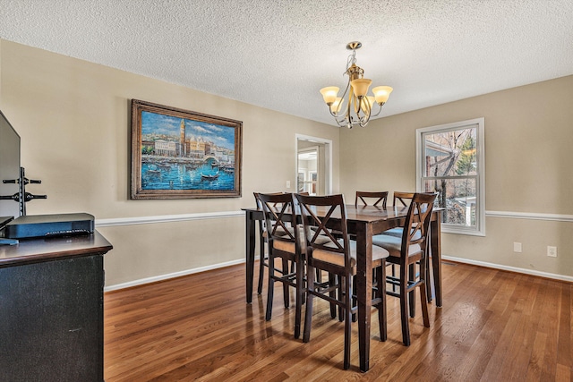 dining room featuring dark wood-type flooring, a chandelier, and a textured ceiling