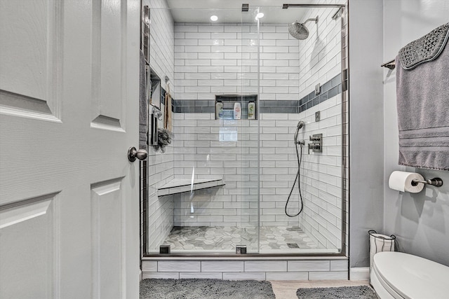 bathroom with a shower with shower door and toilet