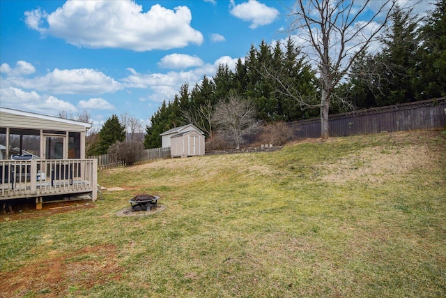 view of yard featuring a storage shed, an outdoor fire pit, a deck, and a sunroom