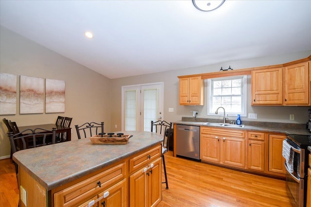 kitchen with a kitchen island, appliances with stainless steel finishes, sink, and light wood-type flooring