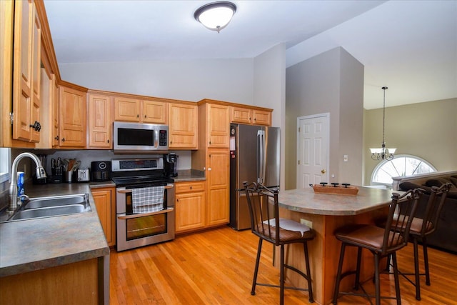 kitchen featuring sink, light wood-type flooring, a kitchen breakfast bar, a notable chandelier, and stainless steel appliances