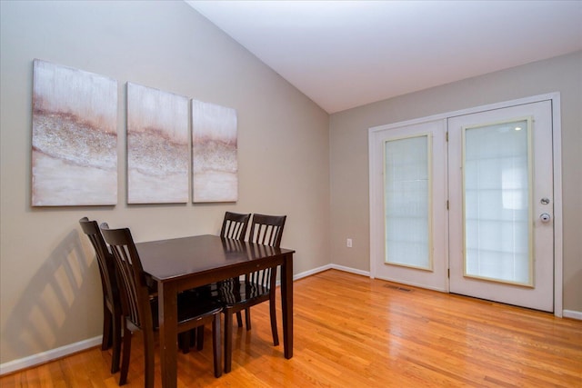 dining space featuring vaulted ceiling and light wood-type flooring