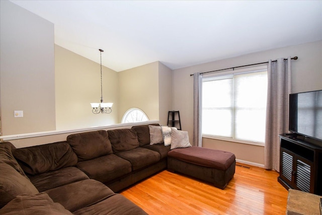 living room with lofted ceiling, a notable chandelier, and light hardwood / wood-style flooring