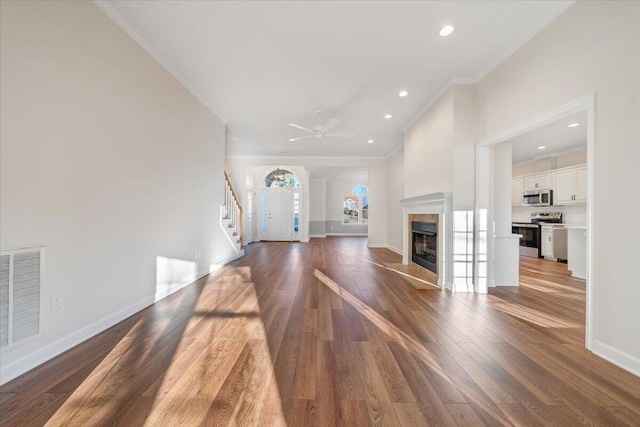 unfurnished living room featuring ornamental molding, dark wood-type flooring, ceiling fan, and a high end fireplace