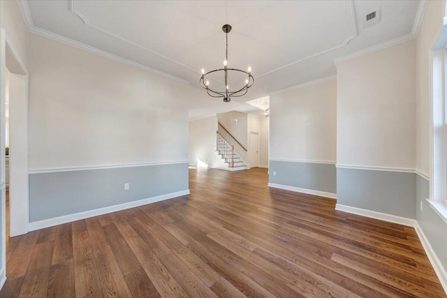 empty room with hardwood / wood-style flooring, ornamental molding, and a chandelier