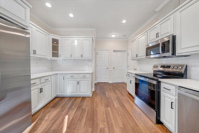 kitchen with ornamental molding, stainless steel appliances, light hardwood / wood-style floors, decorative backsplash, and white cabinets