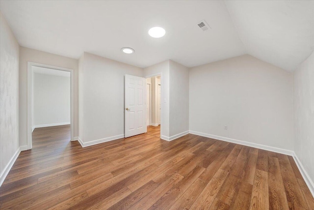 empty room with lofted ceiling and hardwood / wood-style floors