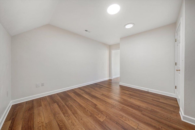 spare room featuring lofted ceiling and dark hardwood / wood-style floors